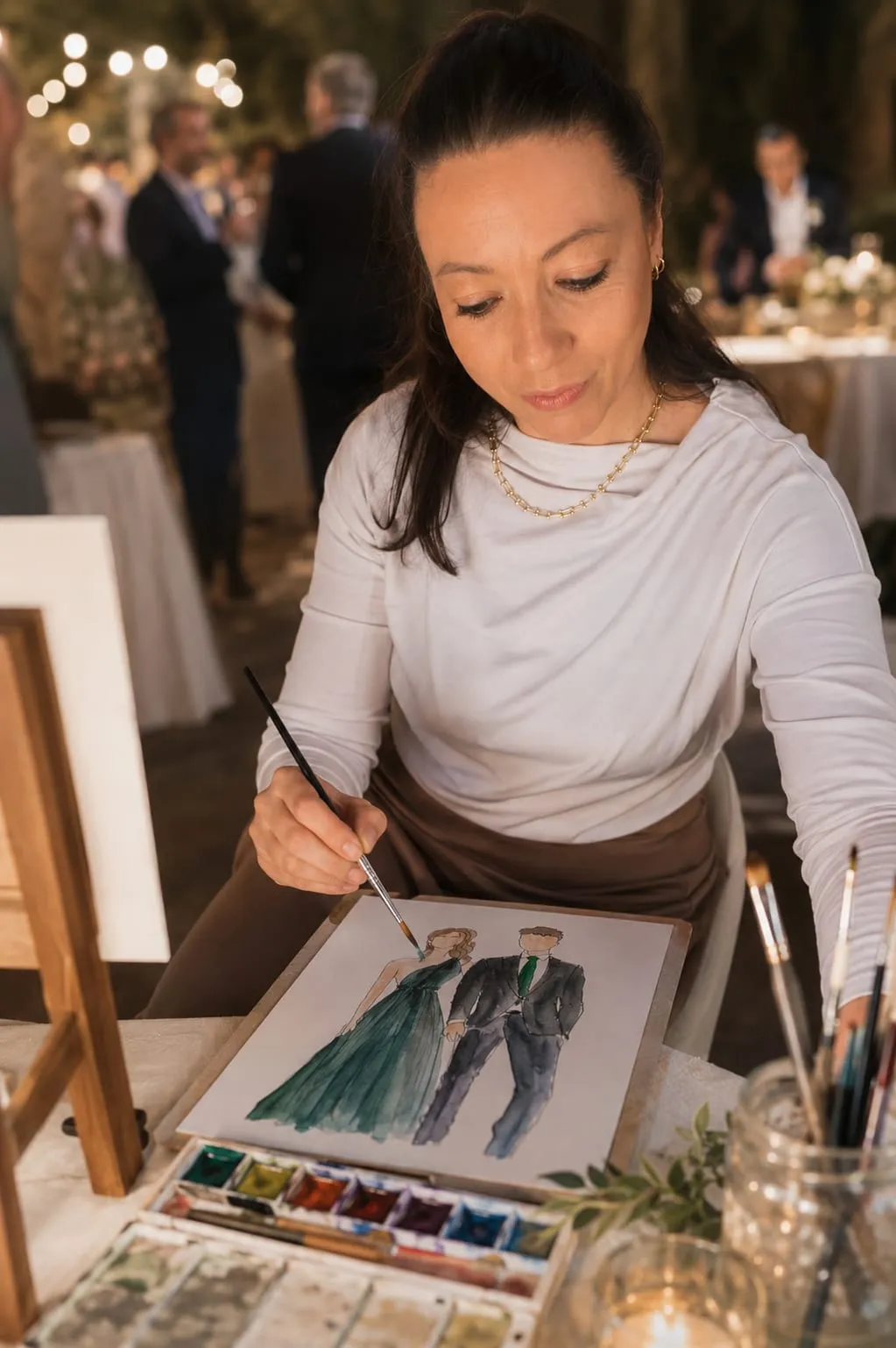 La il·lustradora pintant un retrat amb convidats al fons al capvespre